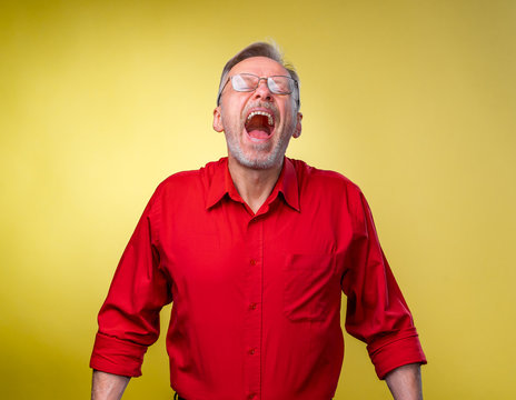 Senior Man Is Standing With Open Mouth And Closed Mouth. Isolated Against Yellow Background. Happy Emotions.