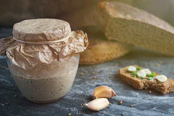 sourdough in glass jar, cloves garlic, bitten sandwich of artisan bread with onion, and cuts loaf rye bread