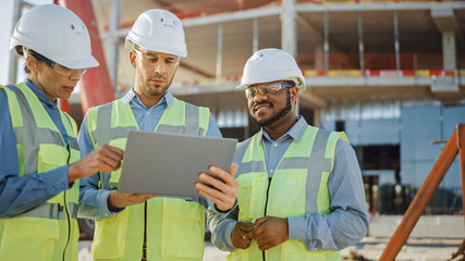 Diverse Team of Specialists Use Laptop on Construction Site. Real Estate Building Project with...