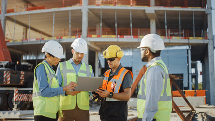 Diverse Team of Specialists Use Laptop Computer on Construction Site. Real Estate Building Project...