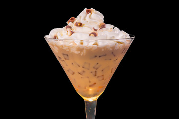 close up of a cocktail served in a martini glass with a dollop of whipped cream with chocolate shavings on black isolated background