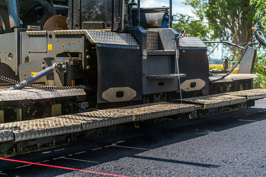 Road repair, compactor lays asphalt. Heavy special machines. Asphalt paver in operation. Side view. Closeup.