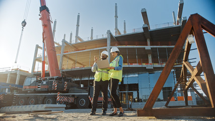 Two Specialists Inspect Commercial, Industrial Building Construction Site. Real Estate Project with...