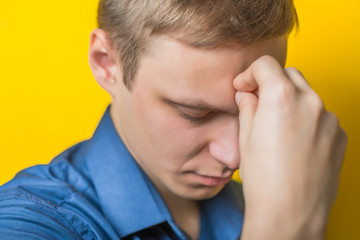 Fototapeta premium Blond young man. Gesture. Man thinks, looking away. Isolated yellow background. Hand on chin, thinking, on a yellow background