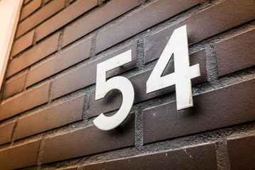 Number 54 on entry house bricks wall - obrazy, fototapety, plakaty