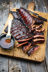 Gegrillte Kalbs Spare Loin Ribs St Louis Schnittt mit scharfer Honig Chili Marinade als closeup auf einem alten rustikalen Hold Schneidebrett  