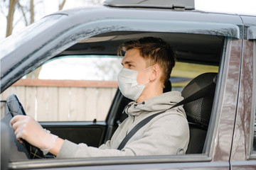 a male driving car wearing protective face mask and gloves