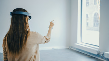 Young Hipster Woman in Holographic Augmented Reality Glasses Standing in Empty Office and Map it....