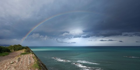 Rainbow on the cliff of Itzurun beach in Zumaia on a stormy day