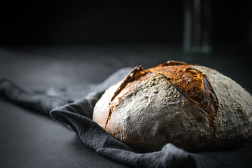 .Bread. Homemade whole grain bread on a dark napkin on a dark background copy space.