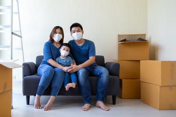 Fototapeta na wymiar Asian family wearing protective medical mask for prevent virus covid-19 during moving day and relocating at new home. Moving house and new real estate concept