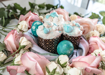 Decorated colorful merengue on the Easter pie. Blue eggs, pink roses.
