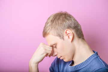 Fototapeta premium Young Man thinks. Put his head on his hand. Profile. Gesture. On a purple background.