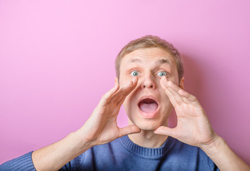 Young man calling, screaming. Gesture. On a purple background.