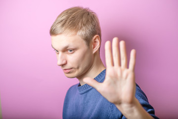 Young man showing stop stop. Gesture. On a purple background.