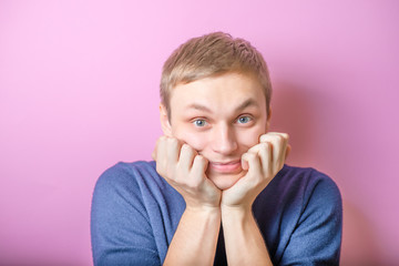 Young man enthusiastically looking at the camera at him, biting his fists. Gesture. On a purple...