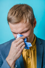 young man blows his nose into a handkerchief