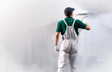 Fototapeta premium Man painting a wall in white color