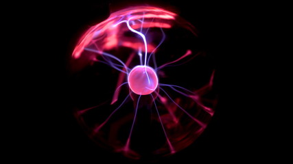 A female hand touches a plasma ball giving out small lightning bolts. Experiments with electricity in the dark.