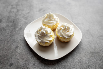 Three mini cheesecakes on a white plate with whipped cream icing 