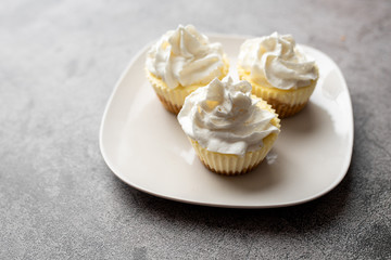 Three mini cheesecakes on a white plate with whipped cream icing 