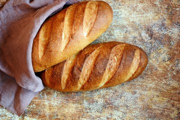 Fresh loaf on a brown background.  Traditional wheat freshly rustic baked bread, loaf of bread.