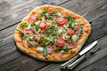 Homemade pizza with mozzarella, parmesan, chorizo, mushrooms and arugula on a rustic background top view copy space..