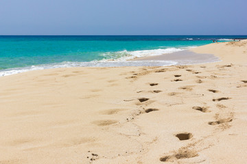 Footsteps along seashore on empty beach with pristine water. Nobody on turquoise color sea of tropical island. Idyllic summer holidays, paradise travel destination concepts