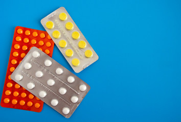 Orange white yellow pills lie on a blue background, the concept of the prevention of viral diseases