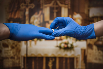 The young couple puts on wedding rings wearing protective gloves. Marriage during a coronavirus epidemic. Covid-19
