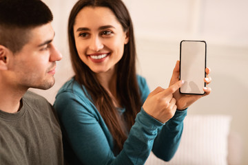 Girl holding and pointing at smartphone with black screen