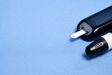 Naklejka premium The glucometer with the test strip on a blue background. space for text