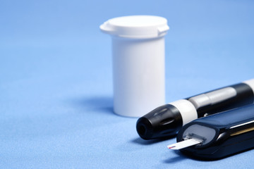 The glucometer with the test strip on a blue background. space for text. selective focus