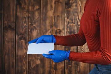 A person in blue protective gloves sends a letter with a correspondence voting card. Elections during the quarantine of the coronavirus epidemic.
