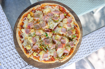Hawaiian Pizza. Pizza topped up with pineapple, ham, onions, cheese, tomatoes, bacon,Bell pepper and sauce. top view