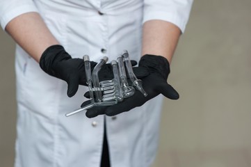 a beautician in black medical gloves holds nozzles for the darsonval apparatus