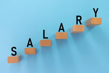 Wooden blocks with salary tag stepping up with arrow on blue background