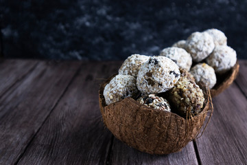 energy ball in a coconut shell on a wooden background close-up, save space, prepare energy bites without baking, mix ingredients such as nuts, cocoa, chocolate, oats, honey, coconut flakes and freeze.
