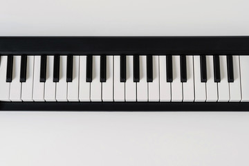 Close up of home synthesizer on a white table. Piano keyboard.