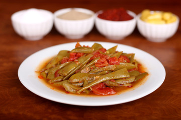 perfect turkish food green beans spicy on white plate close up on wooden table