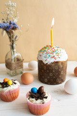 Festive table, Easter cake and Easter eggs on a light wooden background, cupcakes with Easter decor and a bouquet of wildflowers, sweet table for the holiday, Easter Holiday, Easter decor