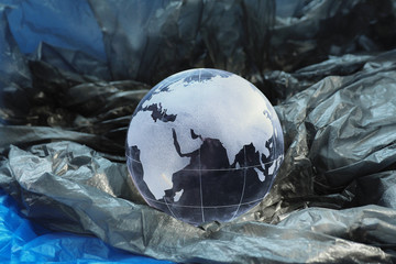 .glass globe with pictured continents Eurasia and Africa with gray and blue package. The concept of clogging the planet with plastic waste..