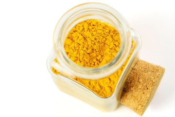 Turmeric powder in glass transparent bottle on the white background, isolated, closeup, top view. Anti-inflammatory remedy, immunomodulator, alternative medicine.