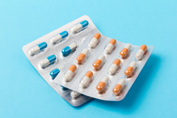 Different tablets, pills in foil blister packs, medical drugs on blue background