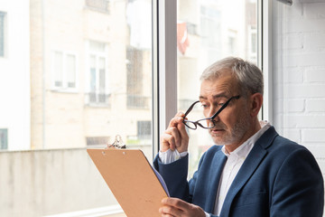 portrait of adult man with documents at home or office by the window