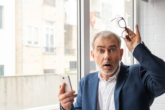 portrait of adult man with mobile phone and expression of amazement or surprise