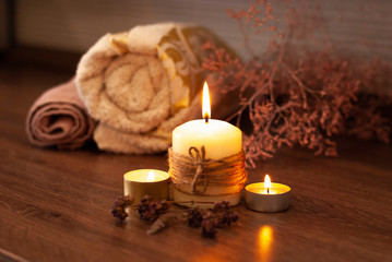 Obraz na płótnie Canvas Beautyful burning light yellow creme vanilla candles with bright flame and towels of natural color in the background