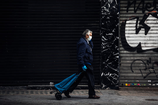 Caballero con guantes y mascarilla va a la compra en el centro de Madrid vacio debido al confinamiento derivado de la pandemia mundial covid-2019