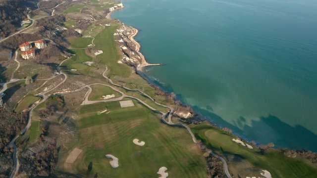 Panoramic video of picturesque landscape with green hills, golf fields and buildings near the rocky coastline of the Black sea, Thracian Cliffs golf and beach resort, Bulgaria.