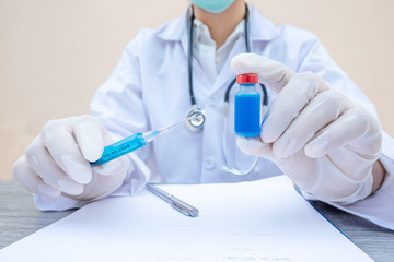 Fototapeta premium The doctor's hand is holding a blue serum tube and syringe